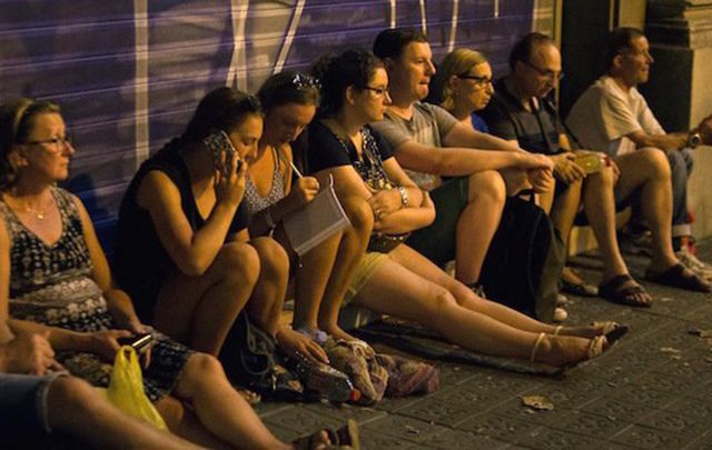 Witnesses look on after the terror attack in Barcelone yesterday in which at least 13 people died. 